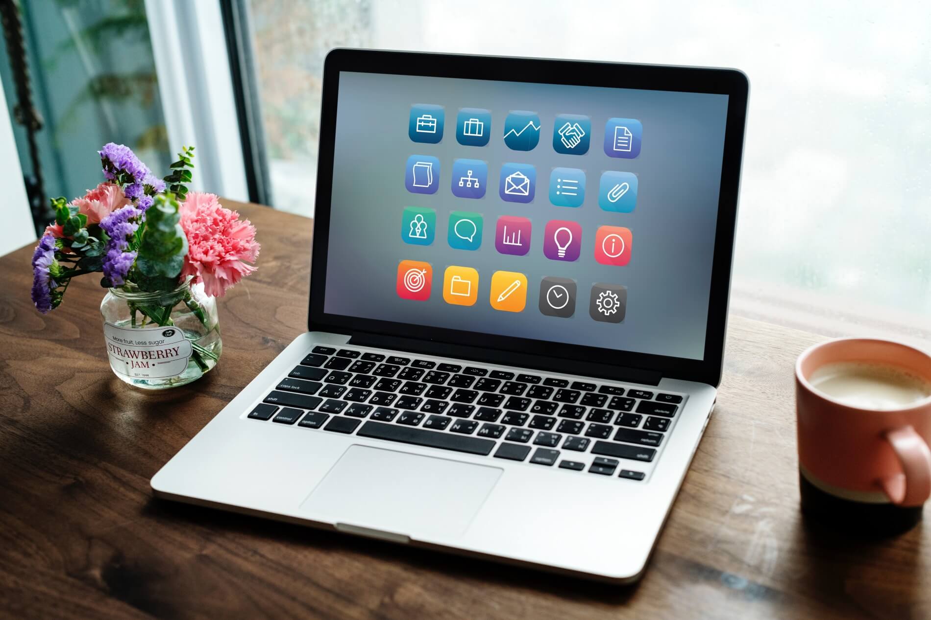 Image showing small coffee, laptop with a small bunch of flowers on a wooden desk by a window