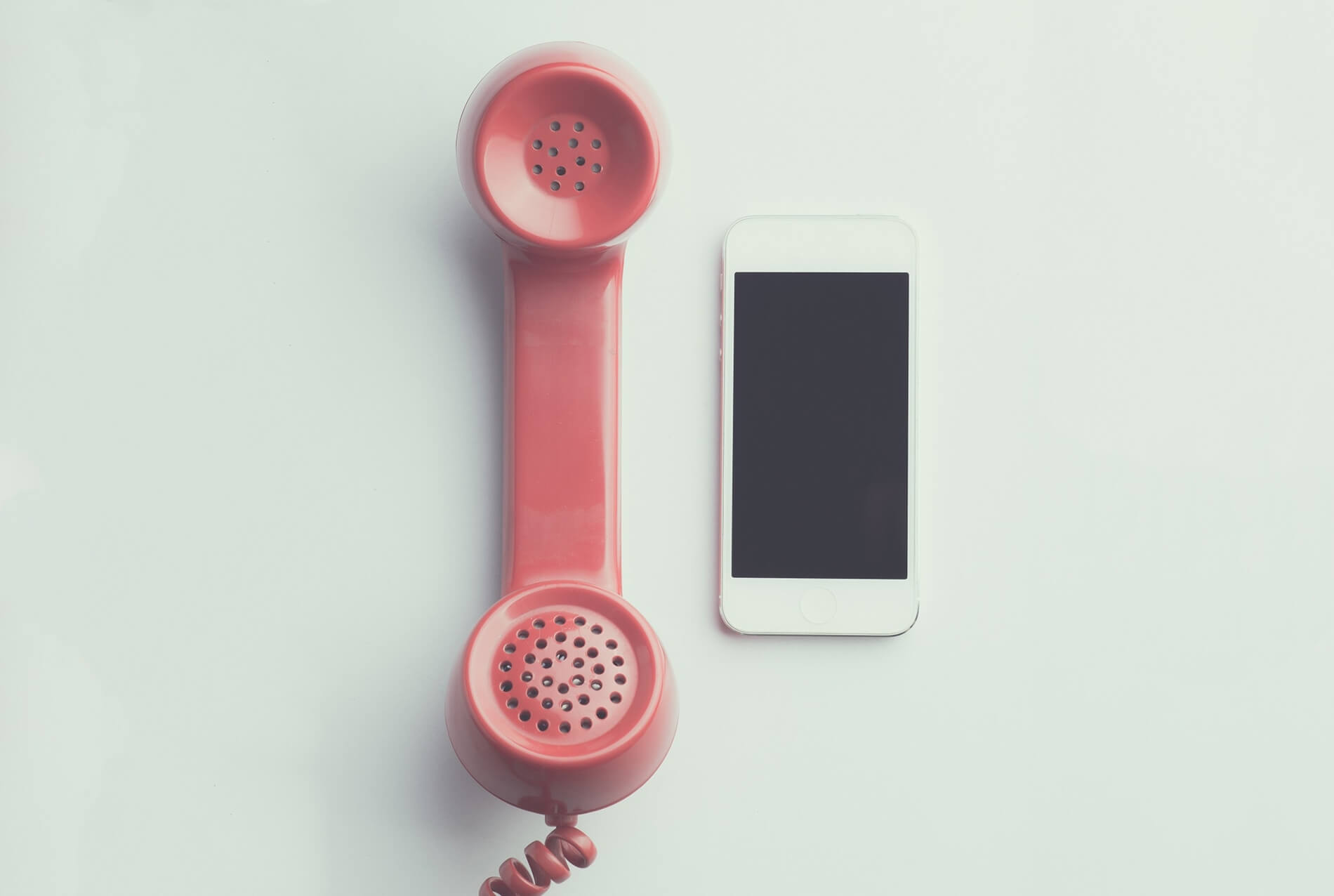 Handheld red phone next to an iphone on a white surface