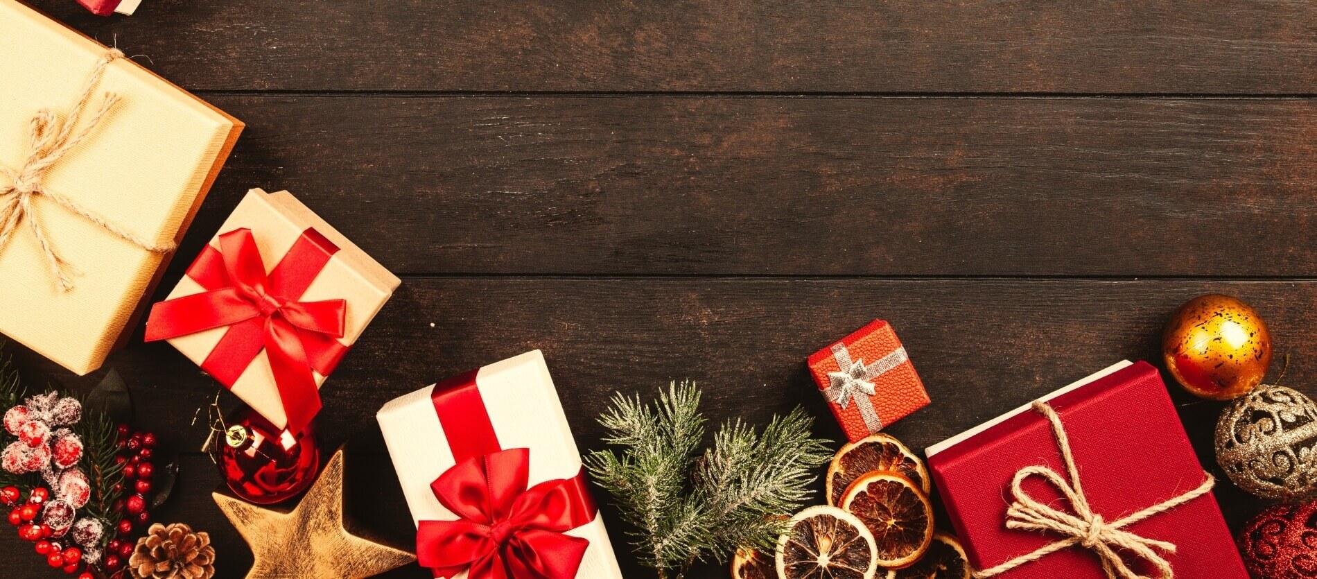 Assorted colored gift wrapped boxes and Christmas decorations on a wooden background