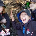 Threeprimaryschoolstudentsagirlandtwoboyssmilingandwavingtheirhandsinexcitementaboutplantingyoungseedlings