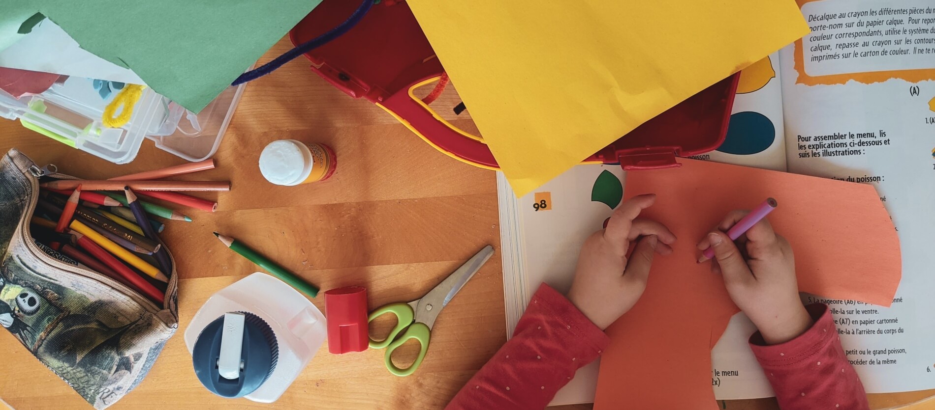 Child doing crafts involving cutting, colouring and cluing paper