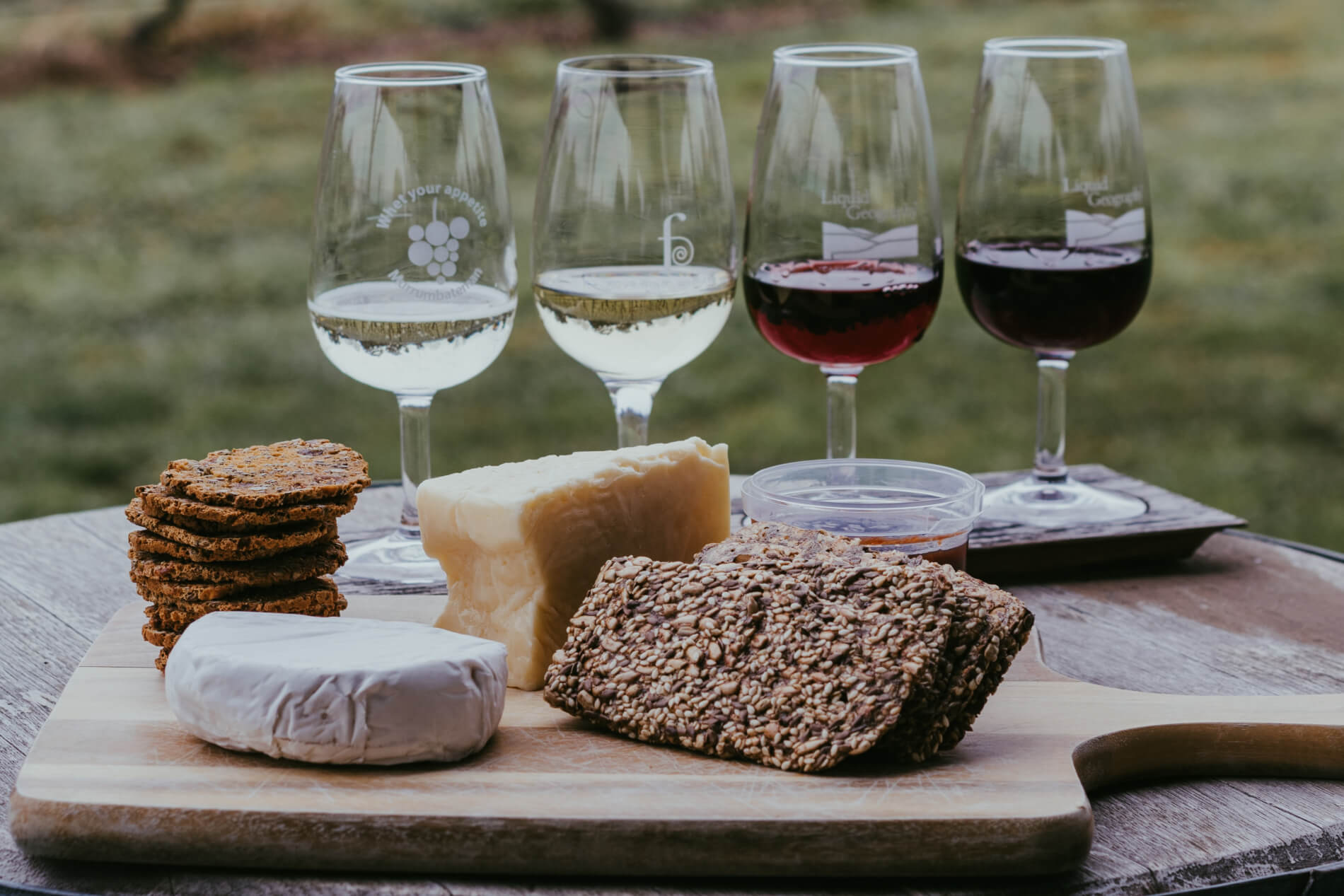 Samples of 4 glasses of wine and a cheese board on a wooden board
