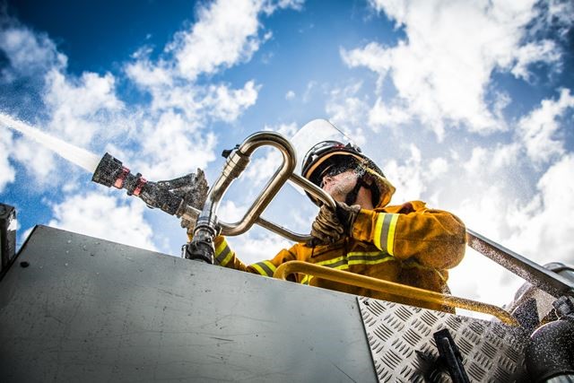 A fire crew member directing the water gun from the fire truck 