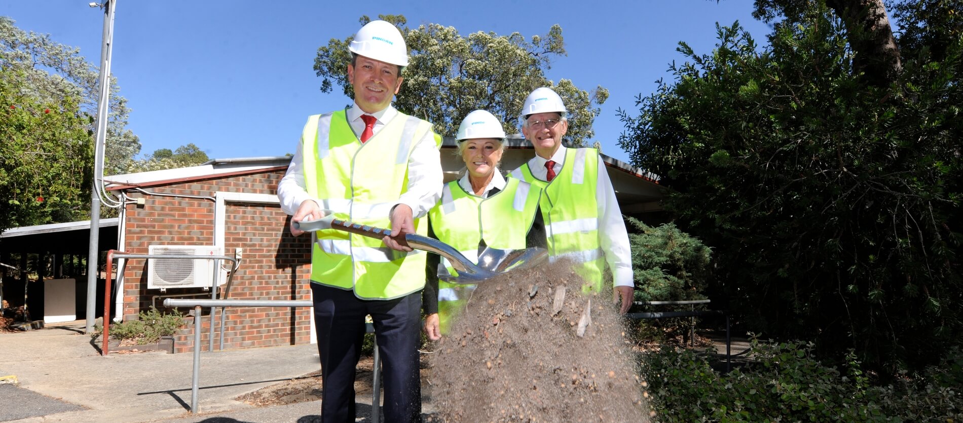 From left Premier Mark McGowan joined with City of Kalamunda Mayor Margaret Thomas, local MP Mathew Hughes. Mark McGown is tipping dirt off the shove he is holding. 