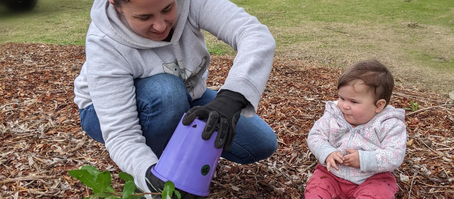 A baby watching on whilst planting during the Commemorative Planting Day 2021