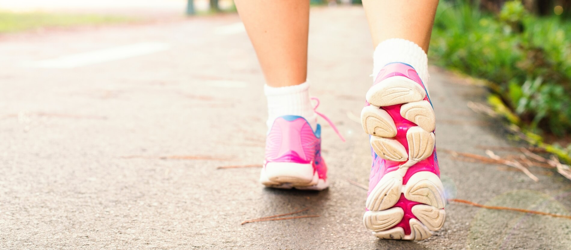 Person wearing pink trainers walking on the right of a pedestrian path.