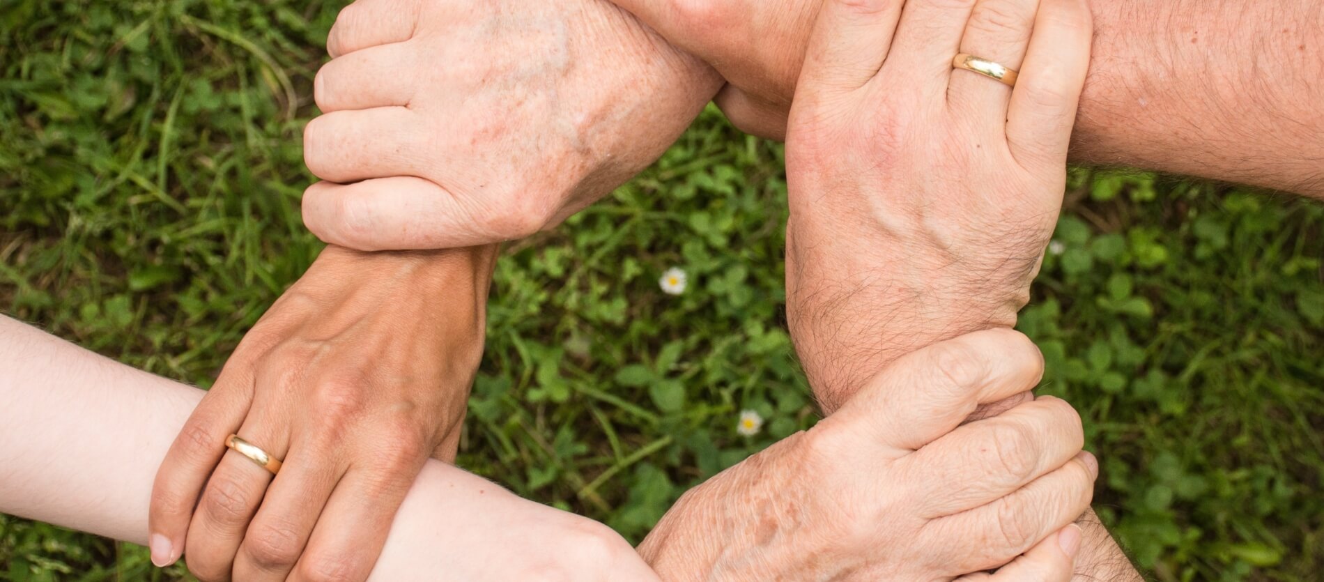 Six hands holding another persons wrist forming a connected circle.