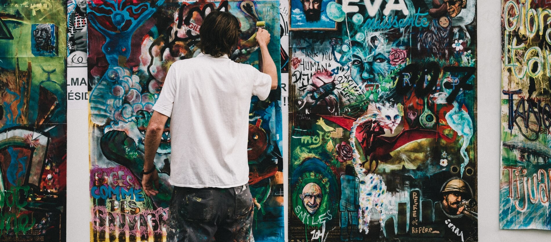 A person wearing a white shirt rolling an arty poster onto a graphic wall