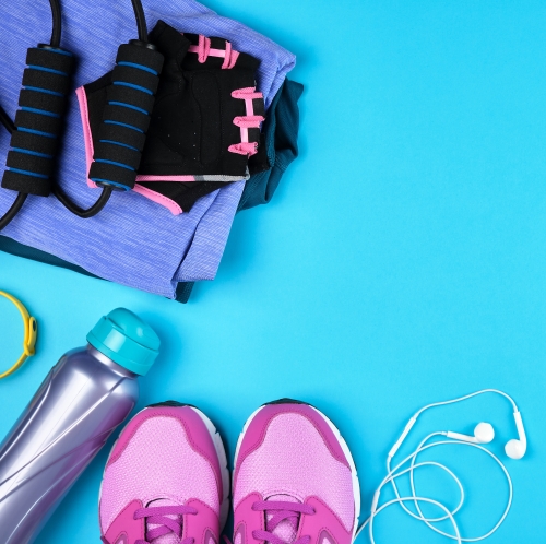 Trainers, earphones, water bottle and gym kit on a blue background