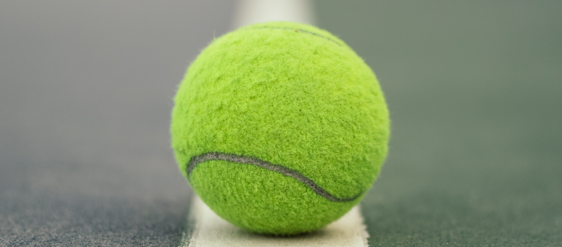 Yellow tennis ball on line of tennis court