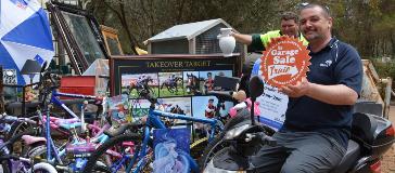 Two City staff holding items and a Garage Sale Trail sign for the Walliston Transfer Station Garage Sale